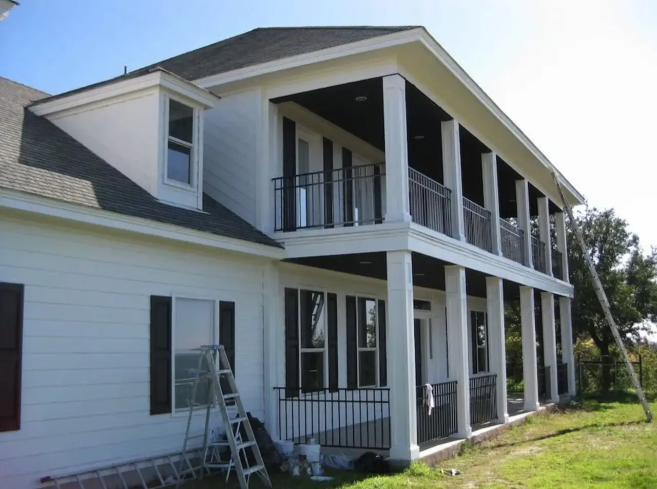 The same double-porch home after repainting in crisp white with black shutters