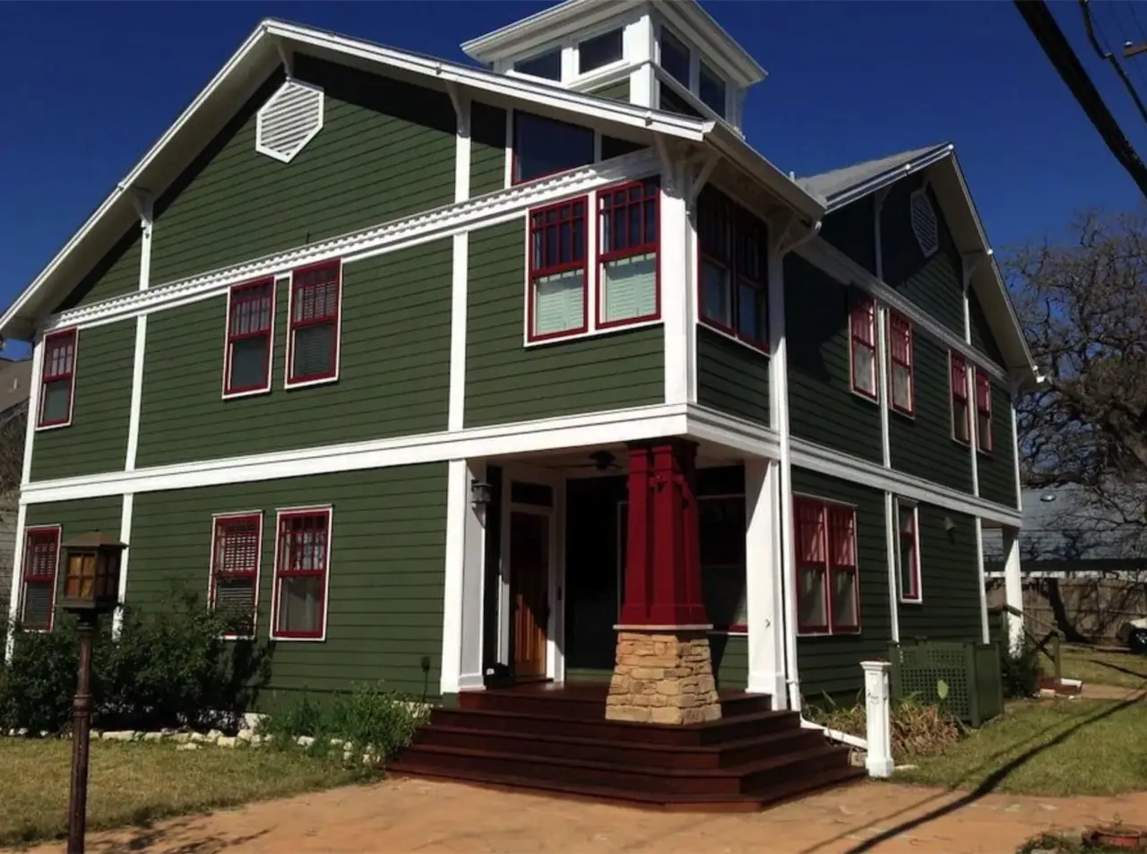 The same craftsman home after repainting in deep green with white and red trim