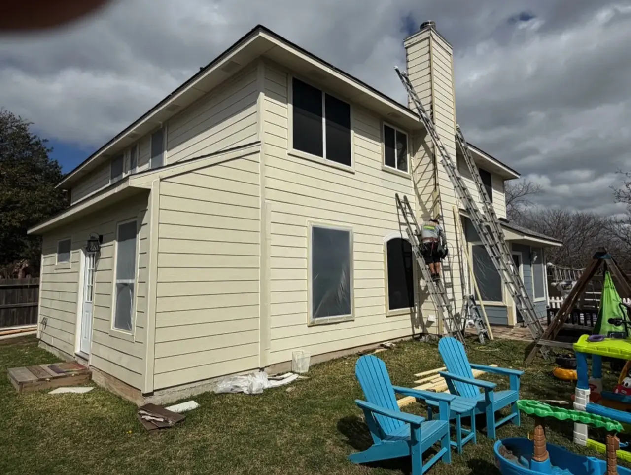 Cream home exterior mid-prep before its light blue repaint