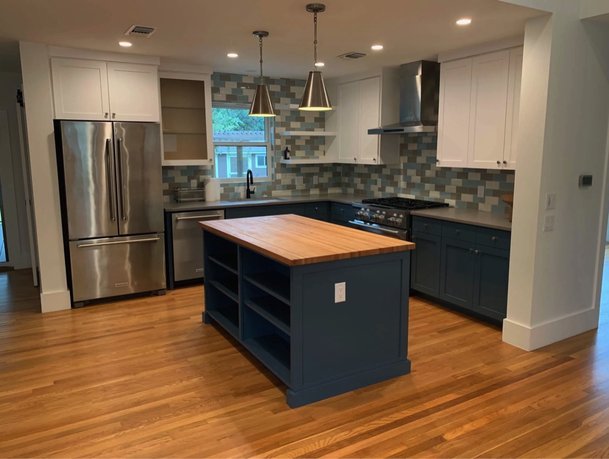 Kitchen repainted with a deep navy island and white cabinetry